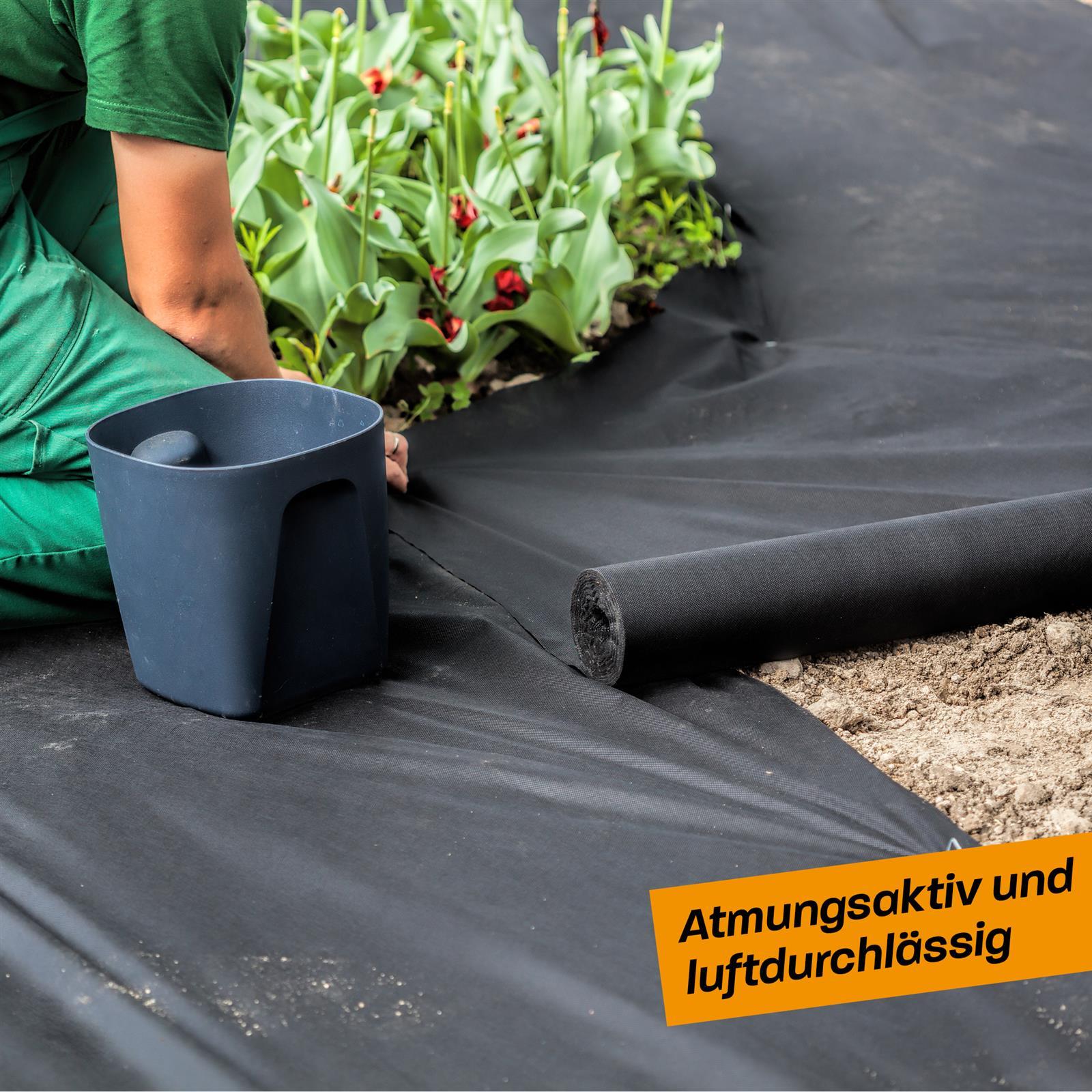 Gartenvlies zur Unkrautbekämpfung und Bodenschutz im Garten – langlebig und witterungsbeständig Ein Mann kniet in einem Gartenbeet und verlegt schwarzes Gartenvlies auf frisch aufgeschütteter Erde, im Hintergrund sind grüne Hecken und Rasen sichtbar.